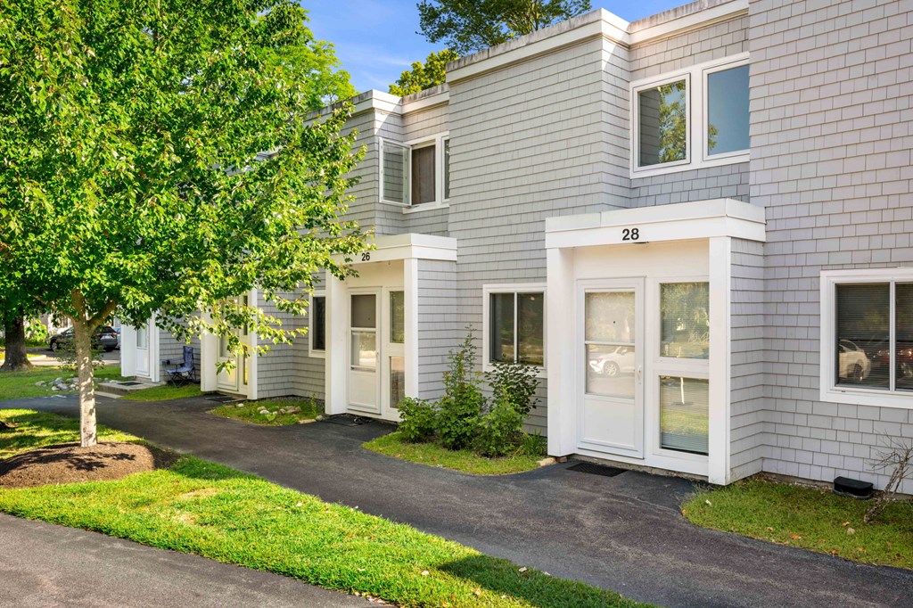 a street view of a white and gray apartment building with trees