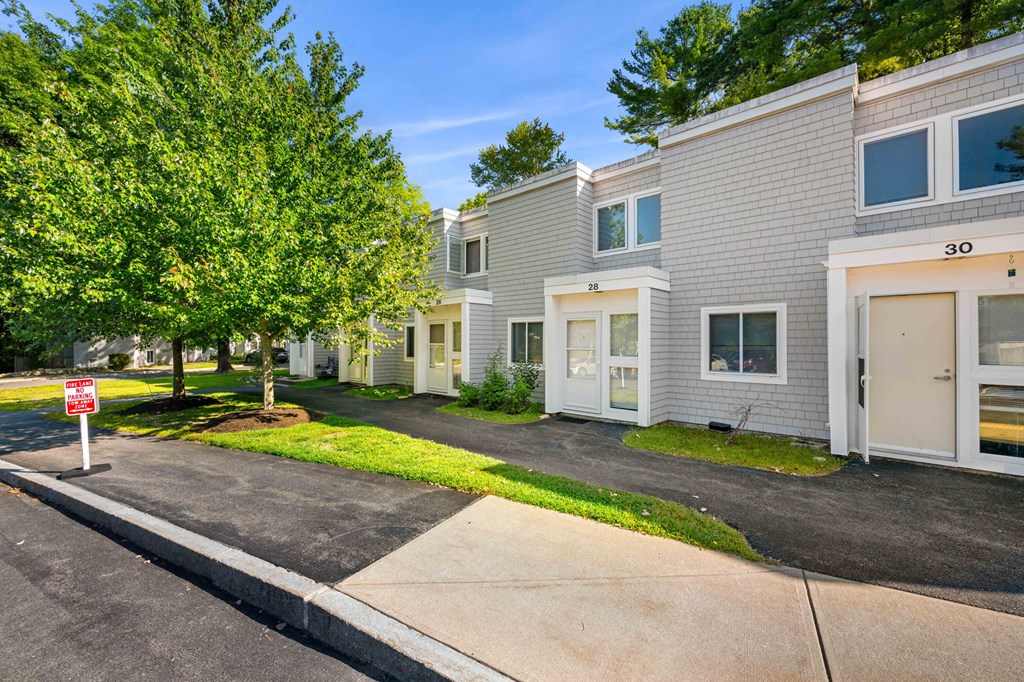 a white apartment building with a driveway and trees