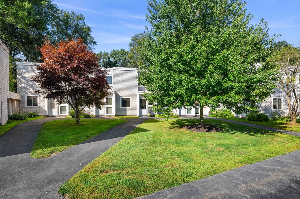street view of apartments with trees and grass with sidewalks