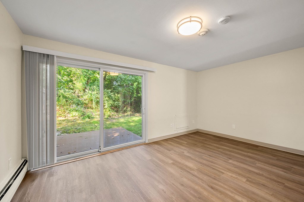an empty living room with a sliding glass door to a yard