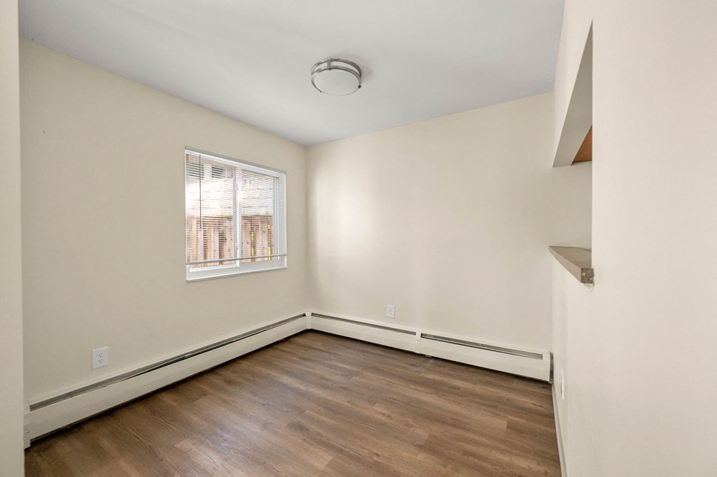 an empty room with wood flooring and a window