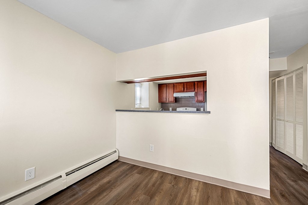 the living room and kitchen of a house with white walls and wood floors