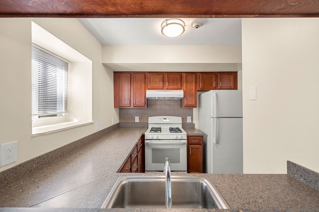 a kitchen with white appliances and wooden cabinets and granite counter tops