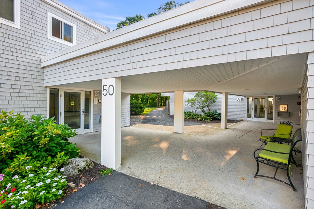 the front entrance of a condo building with a patio and chairs