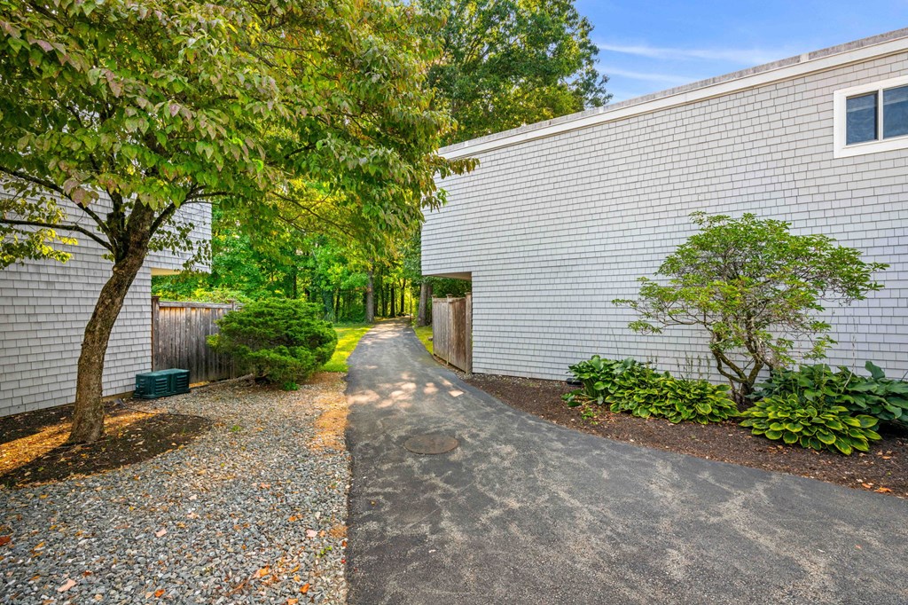 a white house with a paved path next to a tree