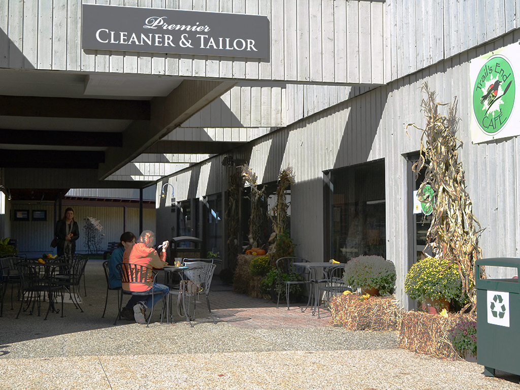 a man sitting at a table outside of a cleaners cleaners and tailor restaurant