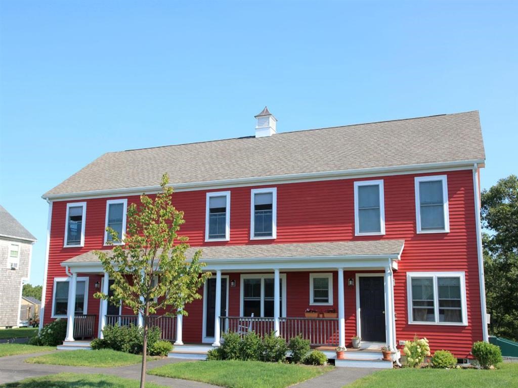 a red house with a porch and a tree in front