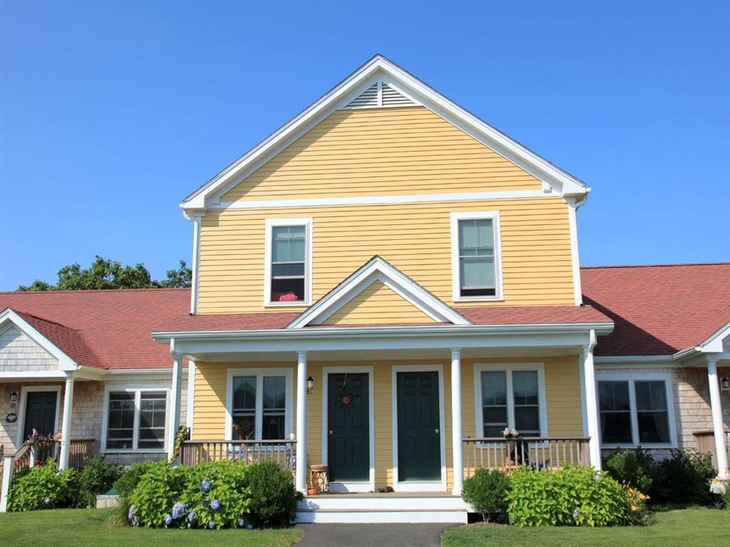 a yellow house with a red roof and a porch