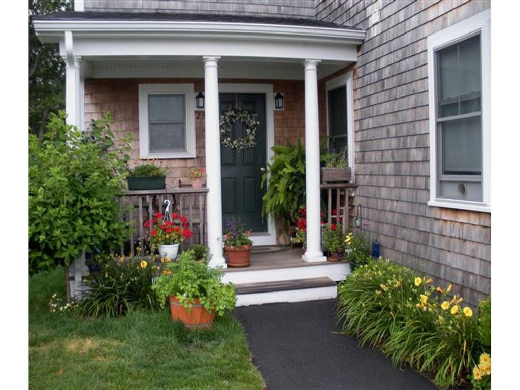 the front porch of a house with columns and potted plants