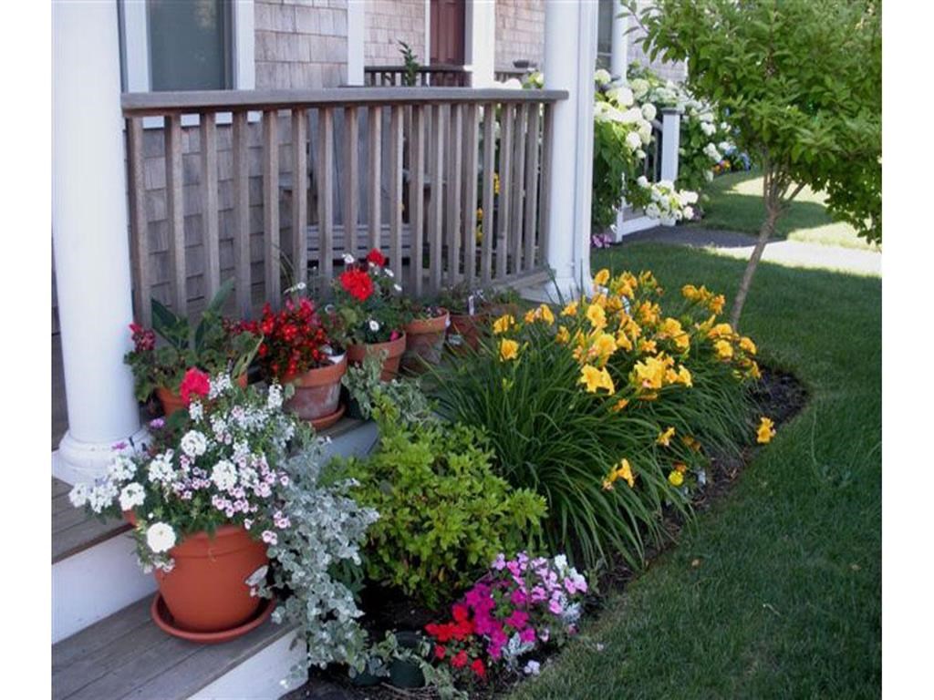 a flower garden in front of a porch