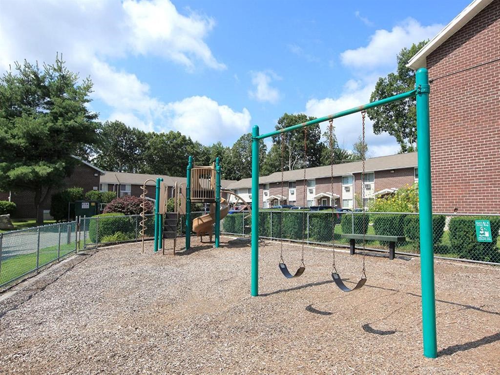 a playground with a swing set and monkey bars in front of a building