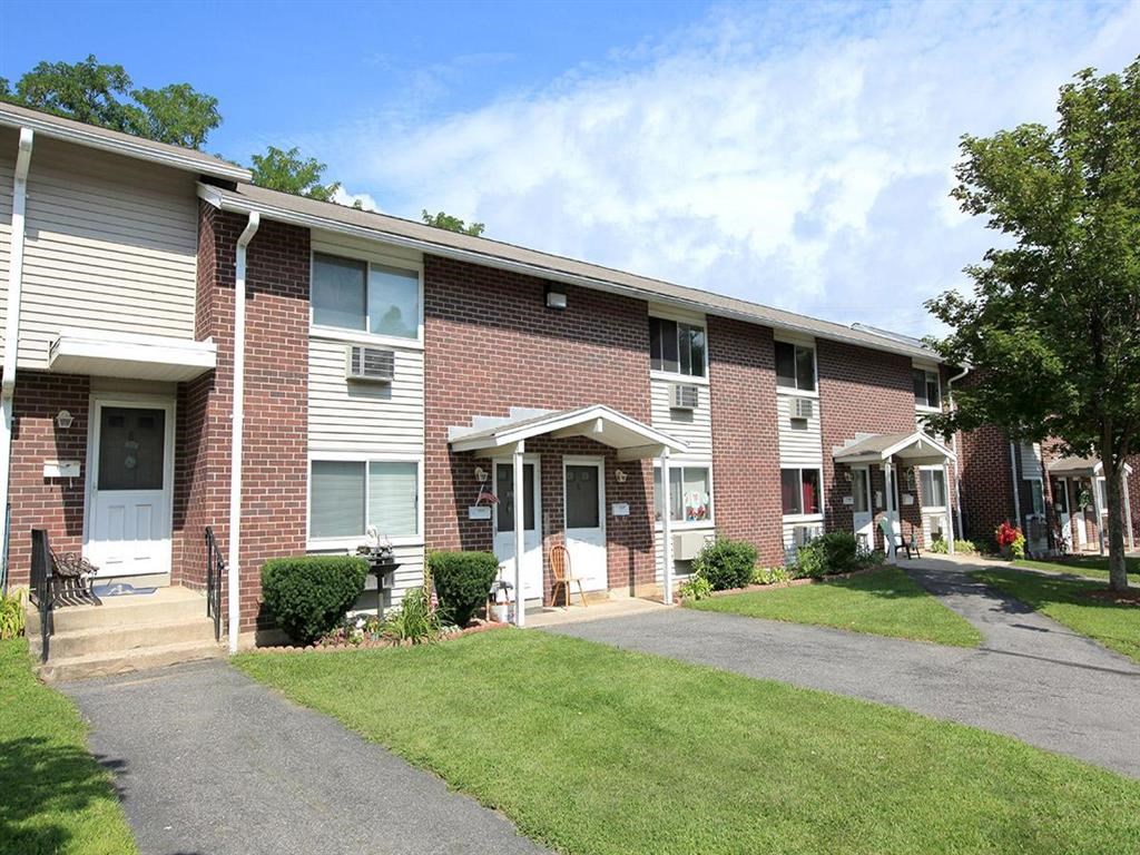 a brick apartment building with a sidewalk in front of it