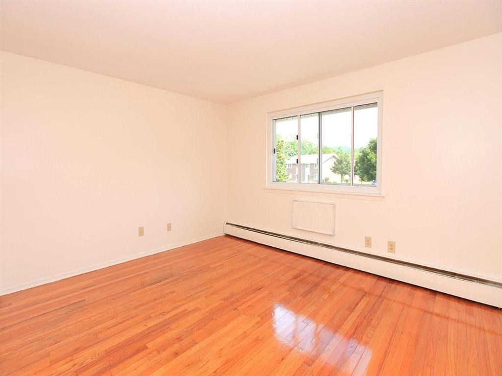 an empty living room with a wood floor and a window