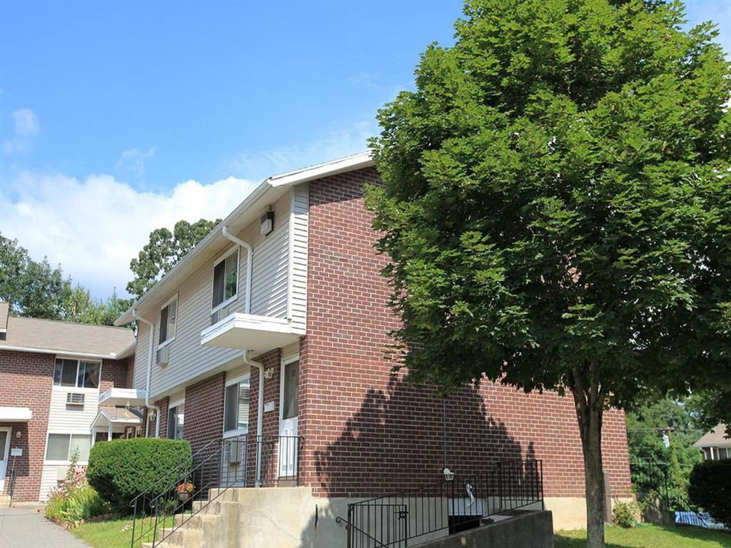 a brick apartment building with a tree in front of it