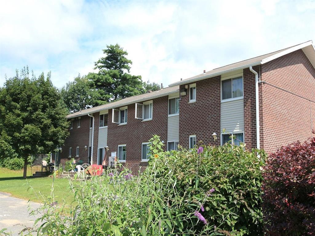 a brick apartment building with a garden in front of it
