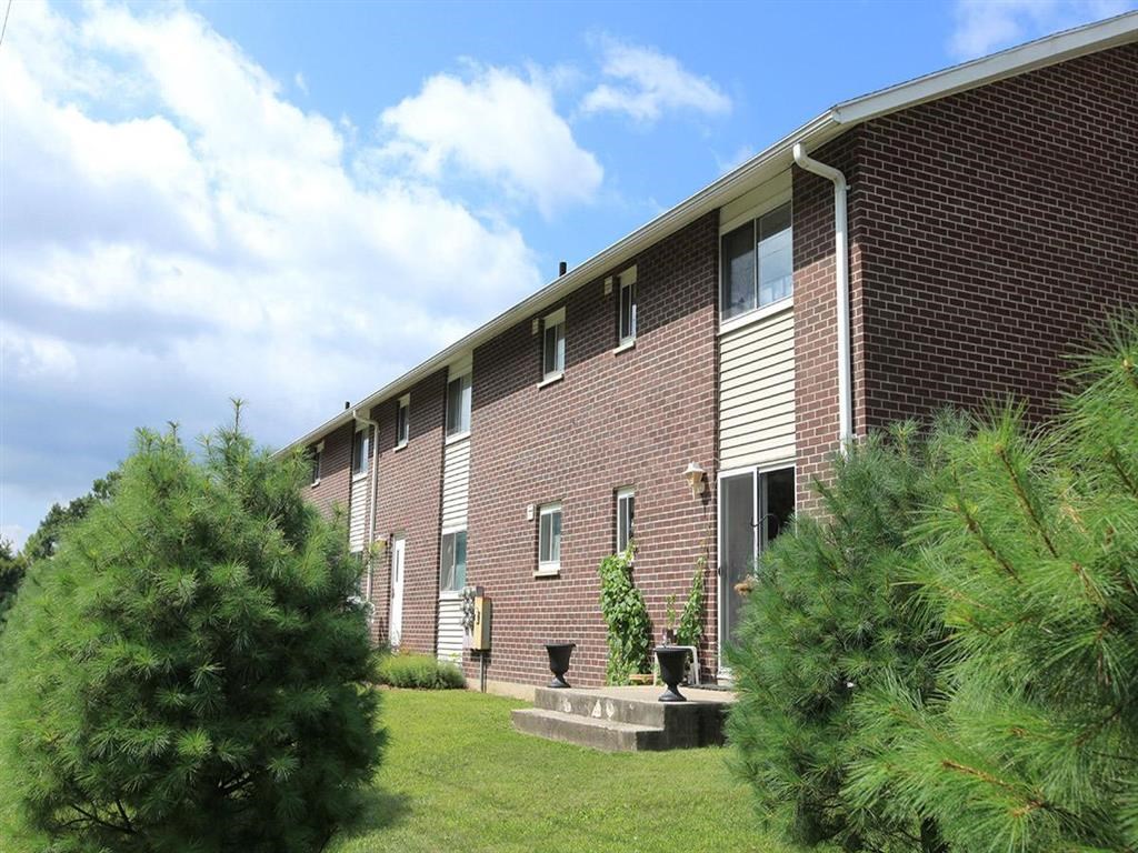 the side of a brick building with trees in front of it