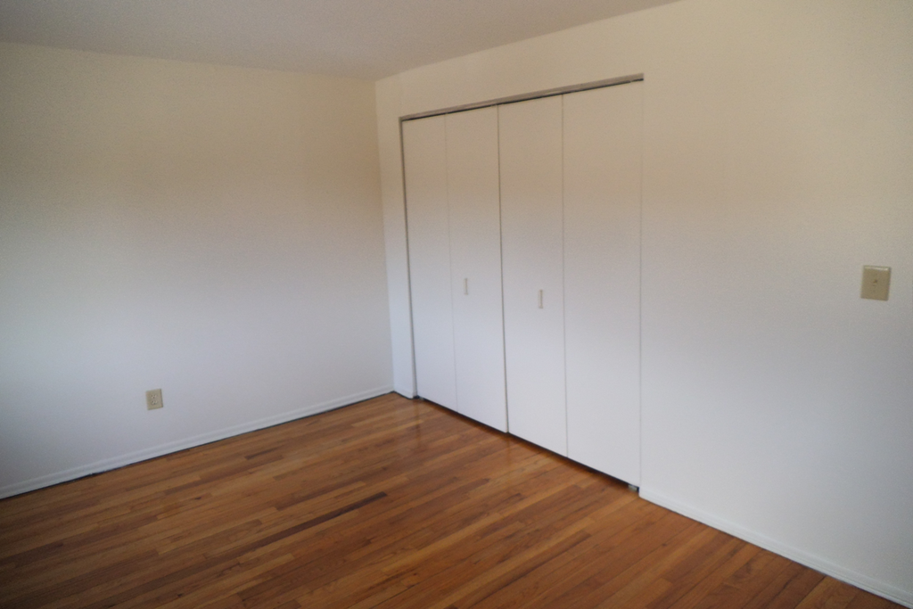 a bedroom with white closets and wood floors