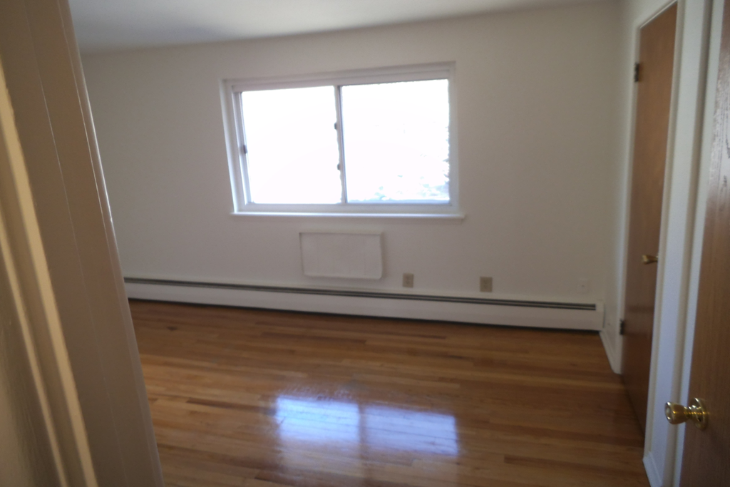 an empty room with a window and wooden floors
