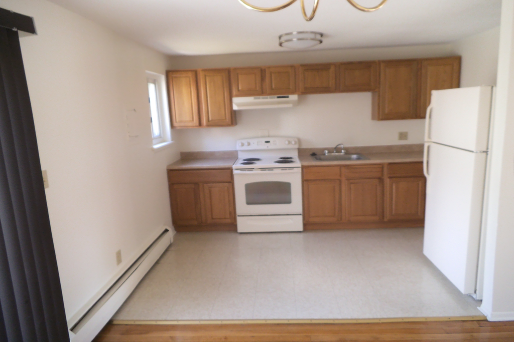 an empty kitchen with white appliances and wooden cabinets