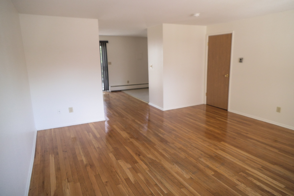 an empty living room with wooden floors and white walls