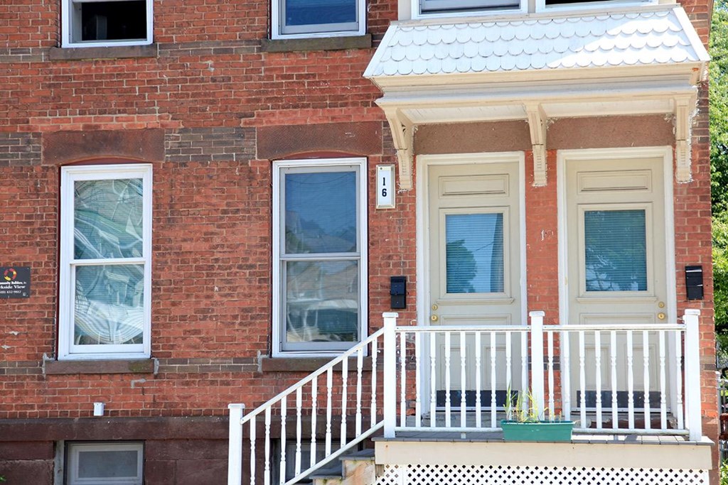 a red brick house with a white porch and a white railing