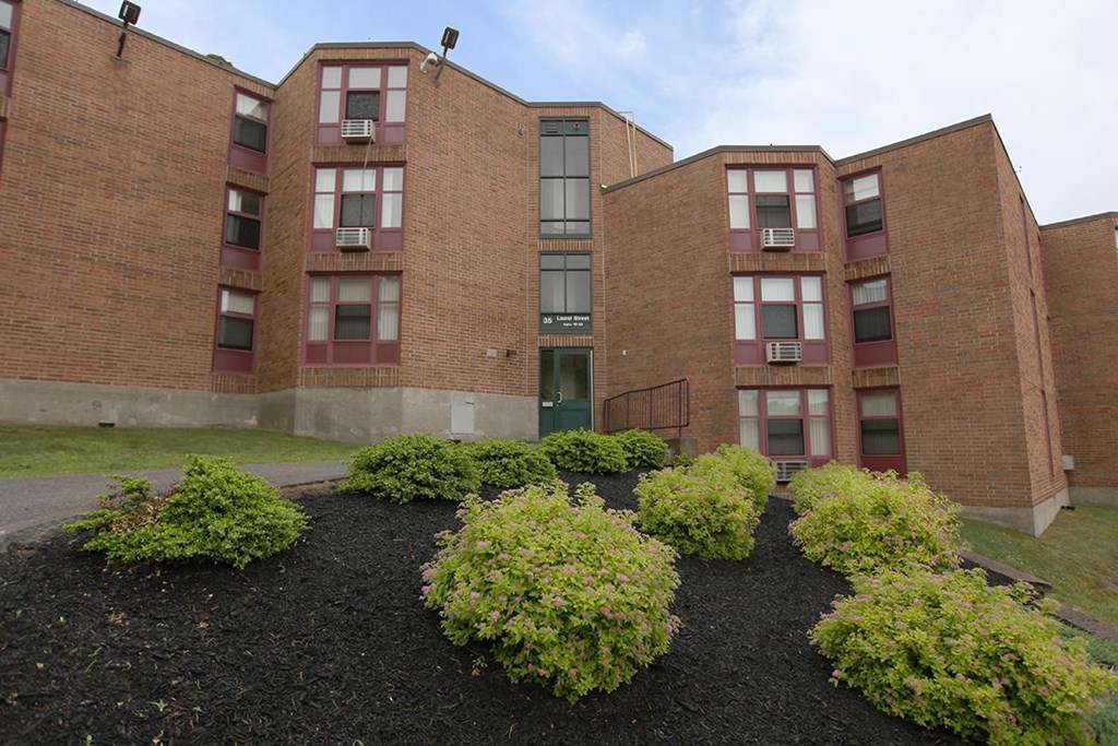 the front of a brick building with some bushes