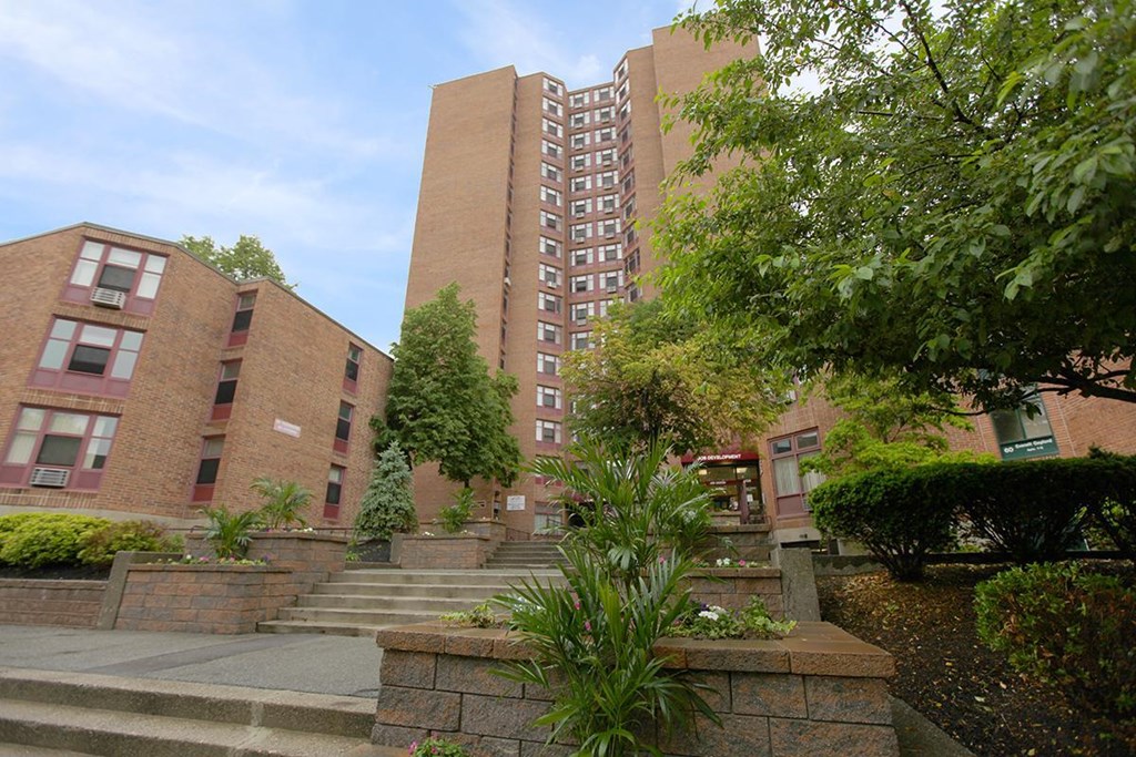 a large brick building with stairs and trees in front of it