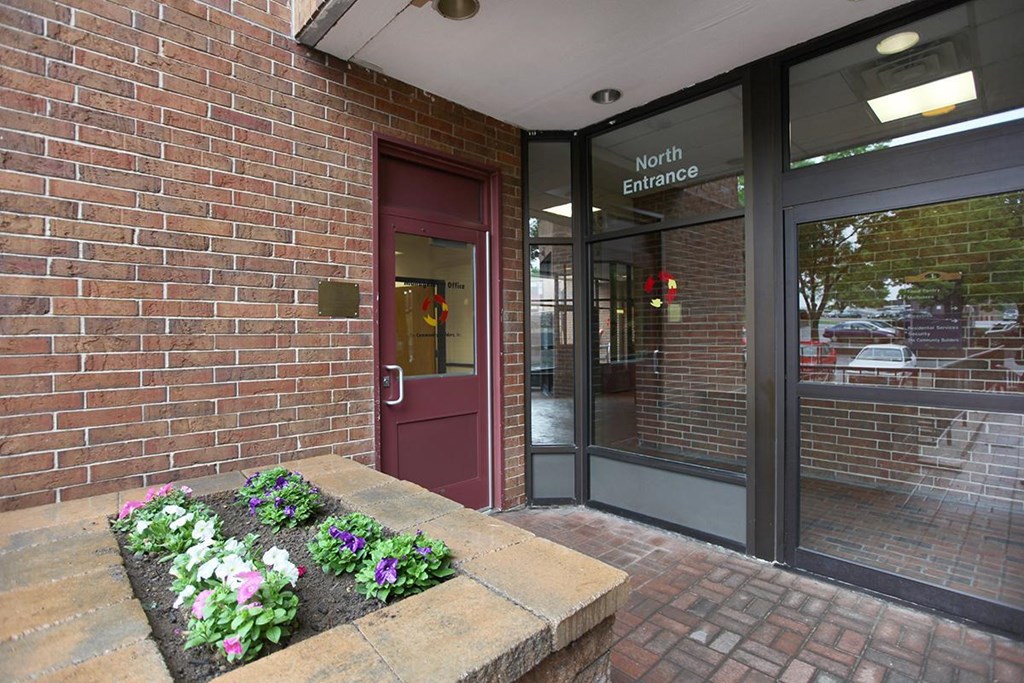 the front entrance of a brick building with a flower garden