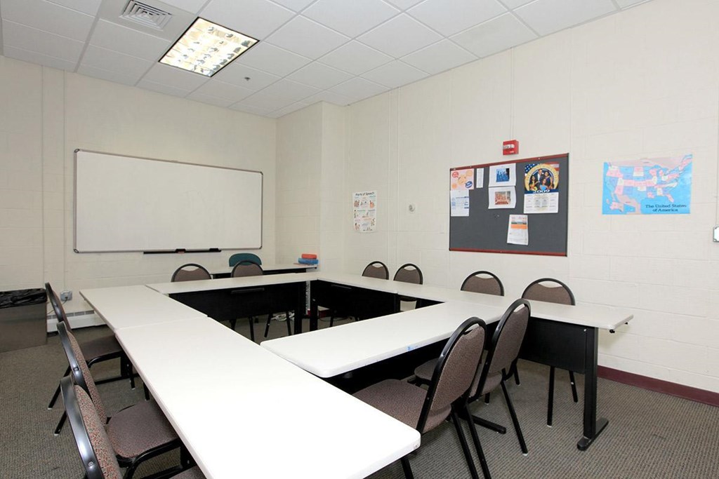 a conference room with tables and chairs and a whiteboard