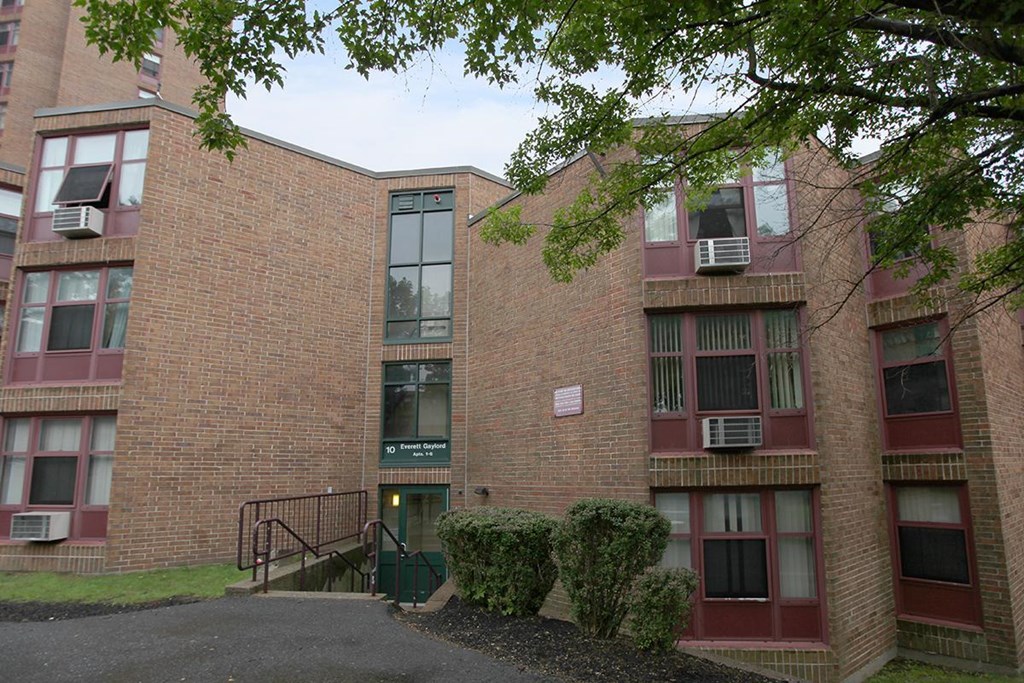 the exterior of a brick building with stairs and trees