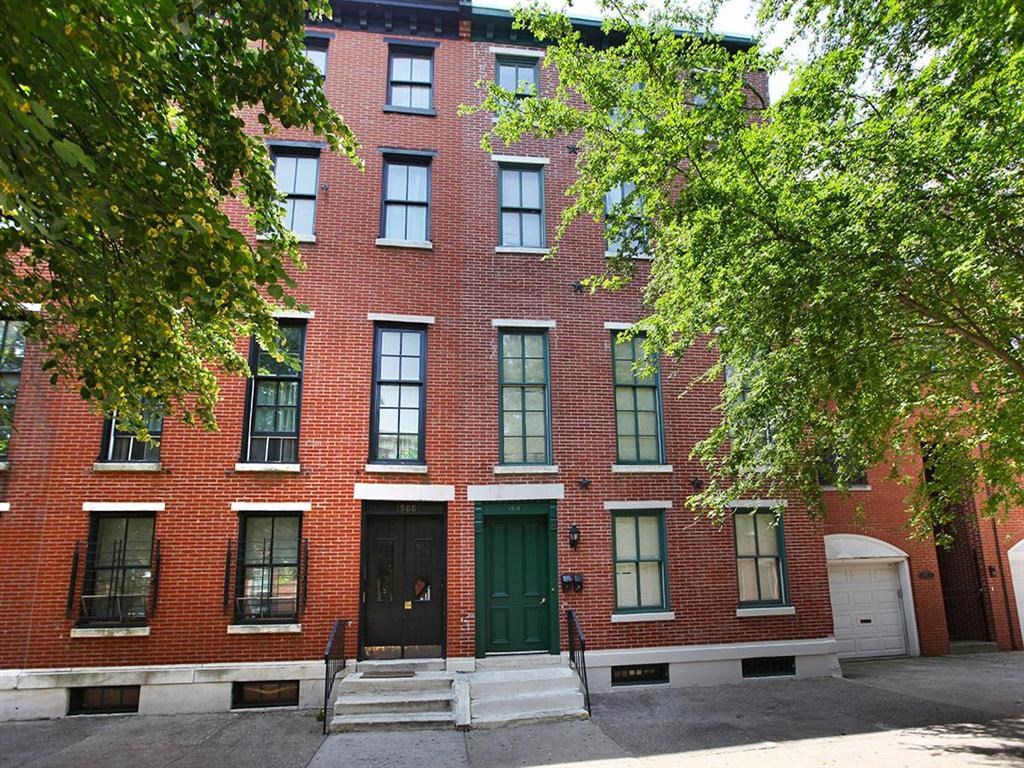 a red brick building with green doors and trees