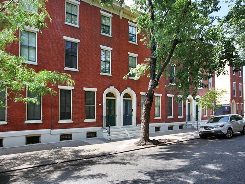 a red brick building on a city street with a tree
