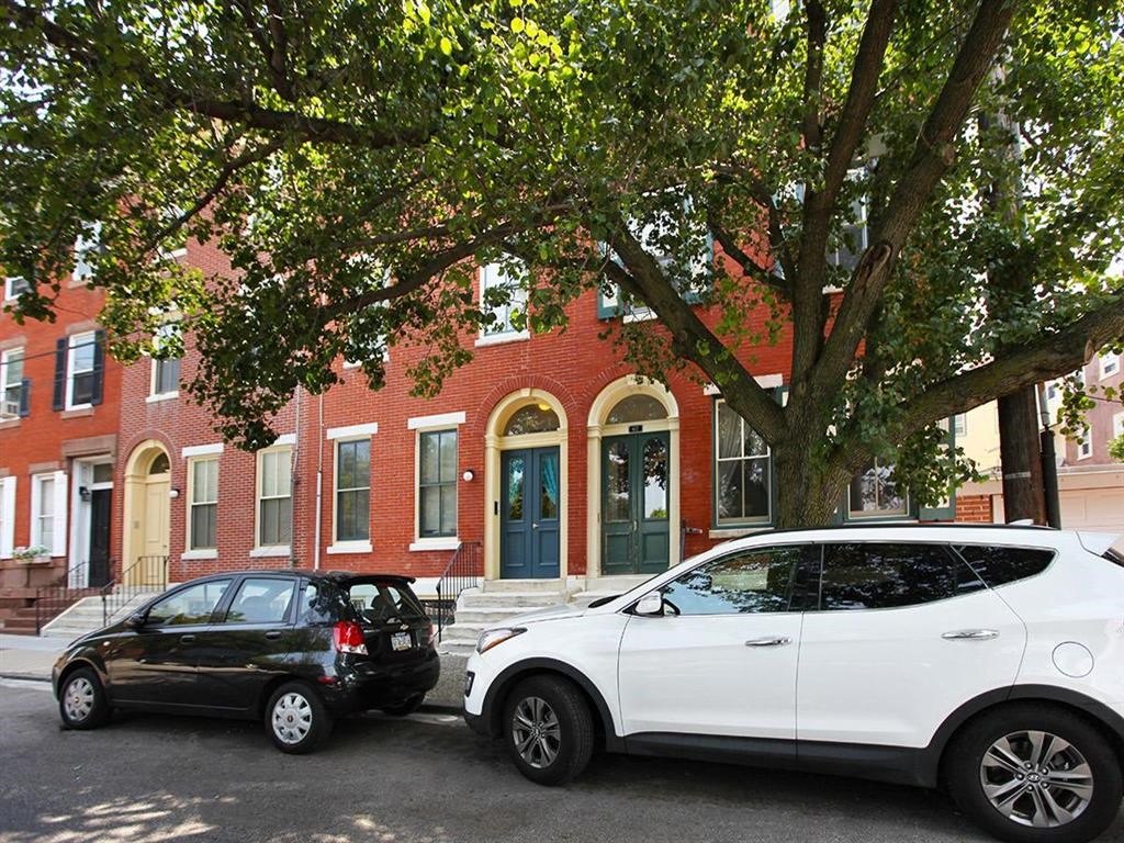 a white car and a black car parked in front of a brick building