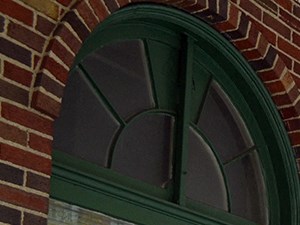 a man walking down a sidewalk in front of a brick building