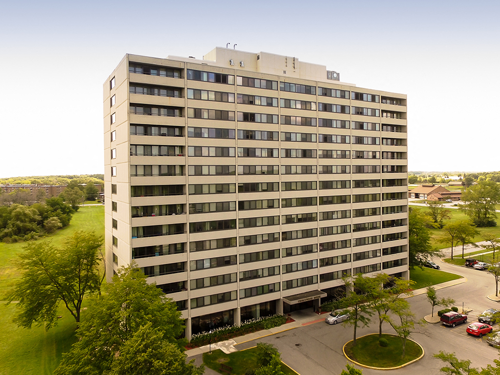 an aerial view of a tall building with trees and a parking lot