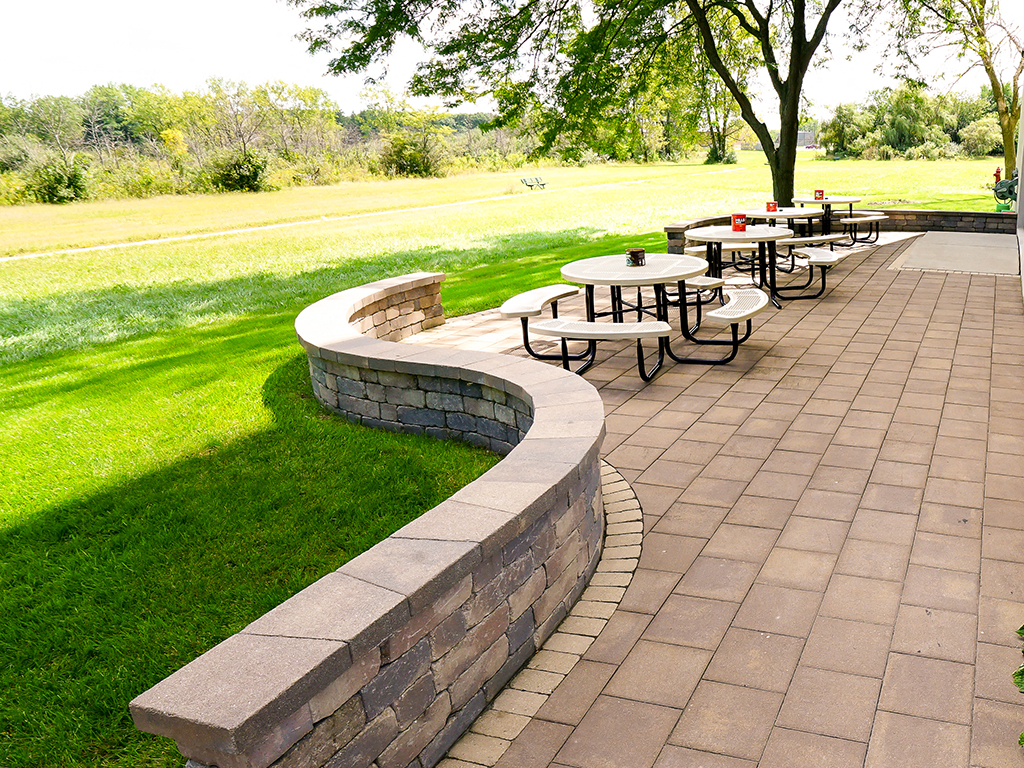 a patio with tables and benches in a park