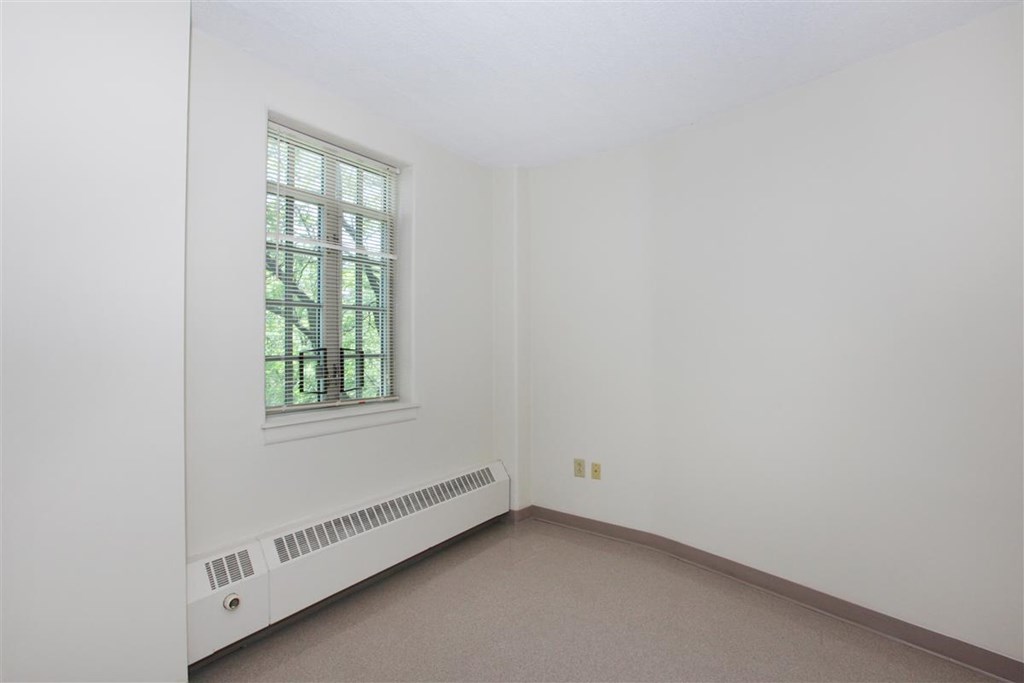 an empty room with a window and a radiator
