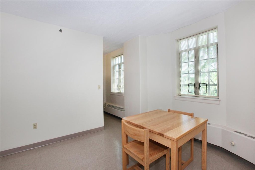 a dining room with a wooden table and two windows