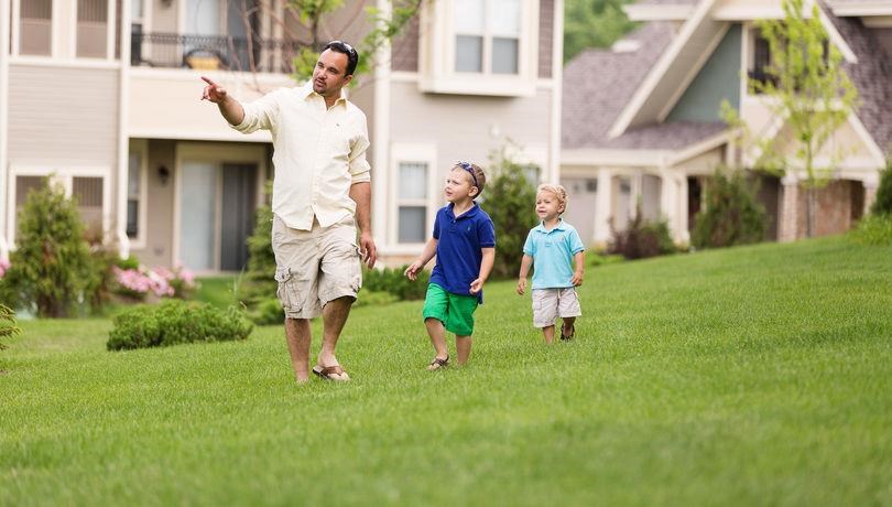 a man and two children walking in the grass