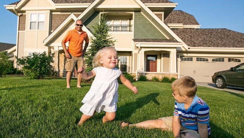 two children playing in the grass in front of a house