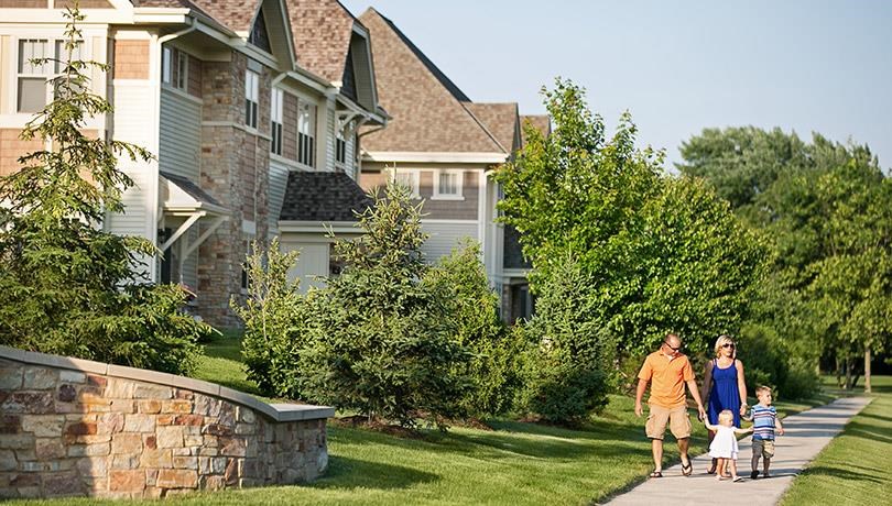 a family walking down a sidewalk in front of houses