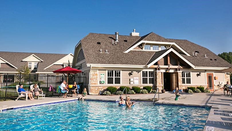 people swimming in a pool in front of a house