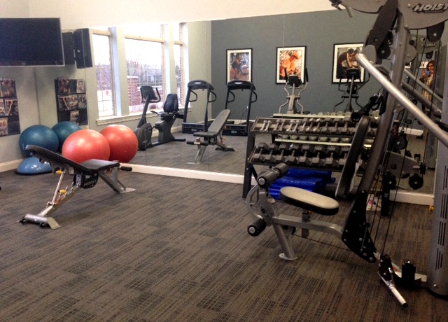 A gym with a variety of equipment including weights and exercise balls.