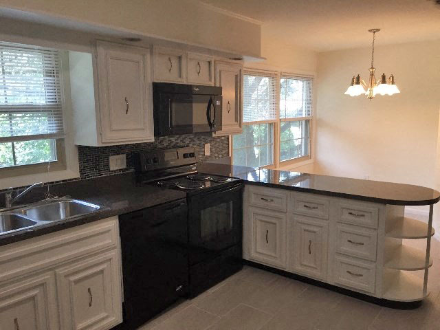 a kitchen with white cabinets and a black counter top
