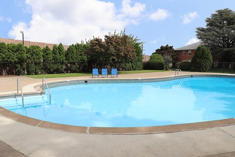 a swimming pool with chairs around it in front of a building