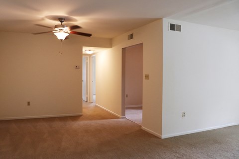 an empty living room with a ceiling fan