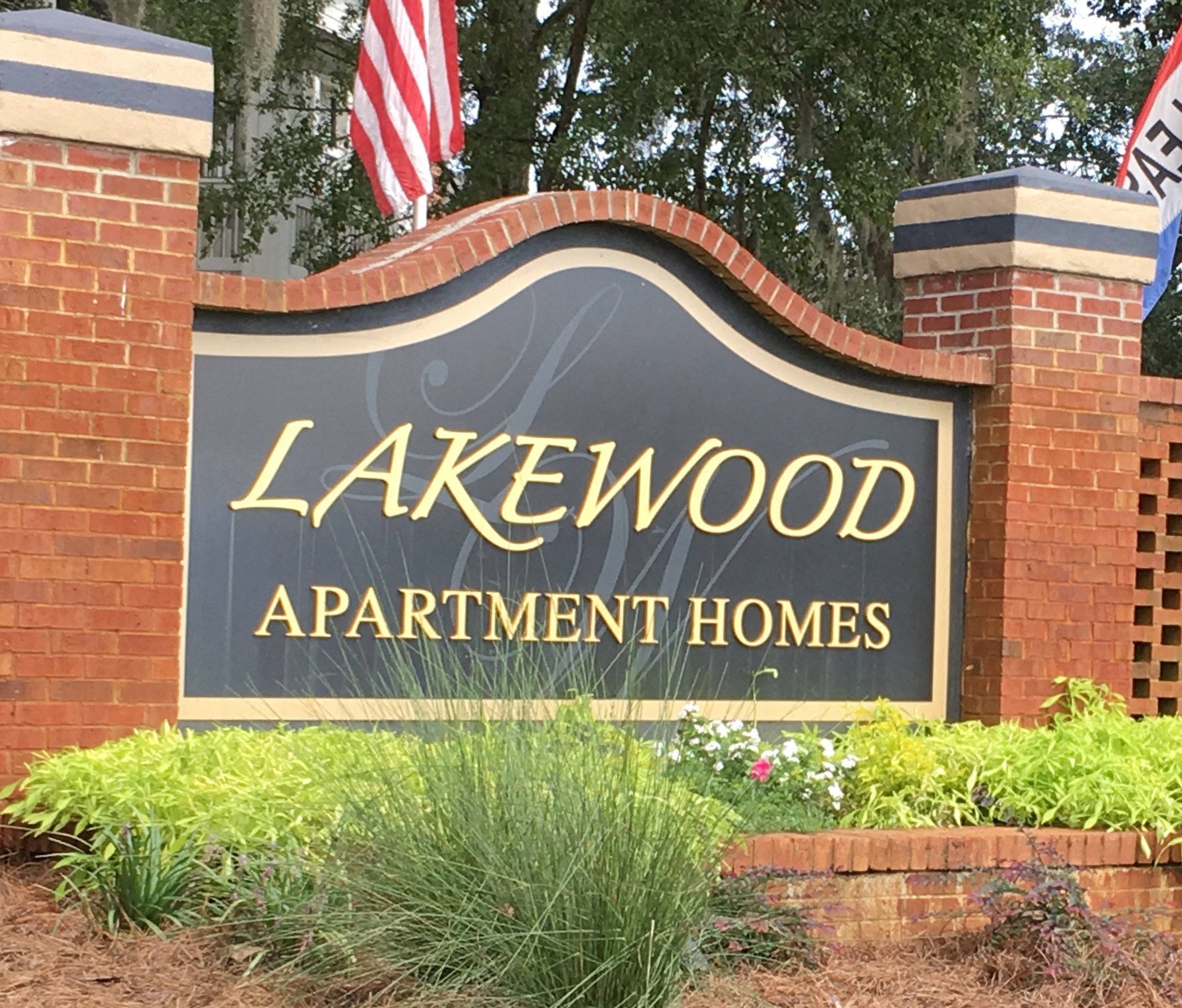 a sign for lakewood apartment homes in front of a brick fence