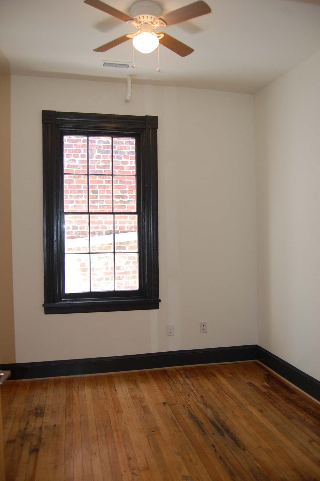 an empty room with a window and a ceiling fan