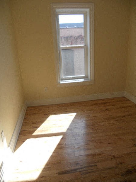 an empty room with a window and wooden floors
