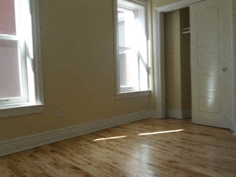 an empty room with two windows and a wooden floor